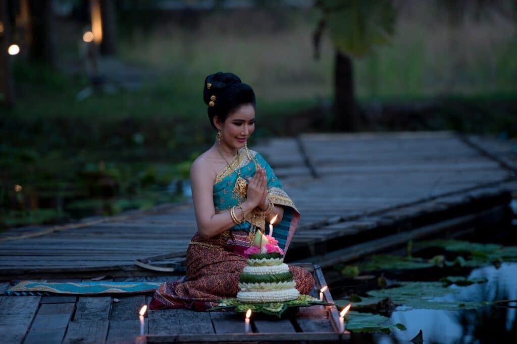 femme priant près d'un krathong