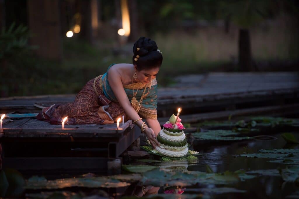 femme met à l'eau un krathong