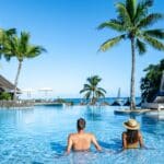 Deux voyageurs savourent le moment dans une piscine luxueuse tout en profitant d'une vue imprenable sur l'océan à l'île Maurice