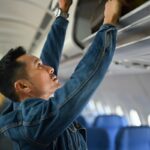 homme qui range un bagage à main dans l'avion