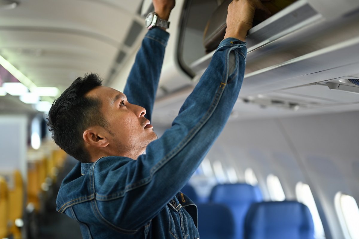 homme qui range un bagage à main dans l'avion