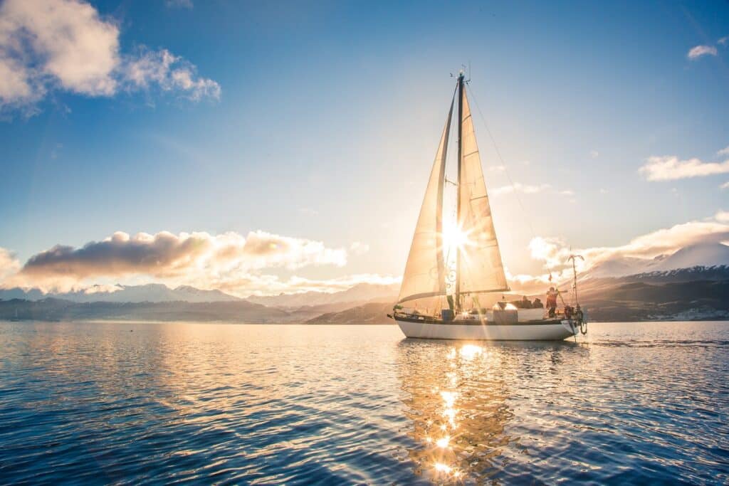 voilier avec la côte et le soleil derrière
