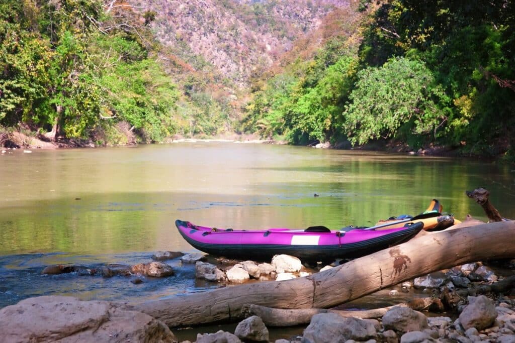 kayak gonflable violet au bord d'une rivière