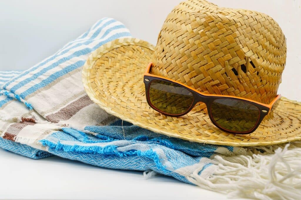 serviette, chapeau de paille et lunettes de soleil