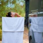 femme qui se douche près d'un van aménagé