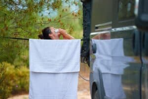 femme qui se douche près d'un van aménagé