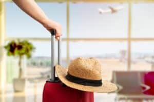bras de femme tenant sa valise pour voyager sereinement