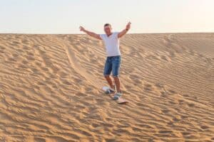 homme surfant sur les dunes de sable au Moyen-Orient