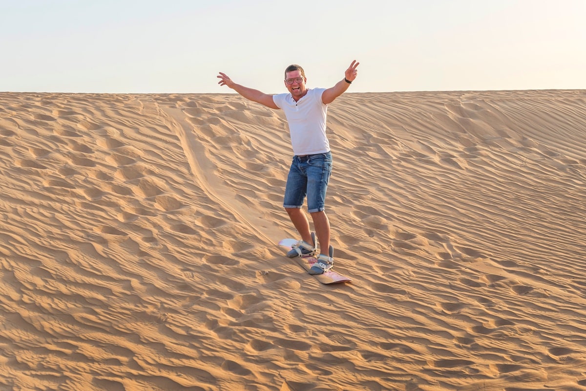 homme surfant sur les dunes de sable au Moyen-Orient