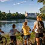Une famille à vélo profite d’une balade au bord de la Loire, face à un château du Loiret